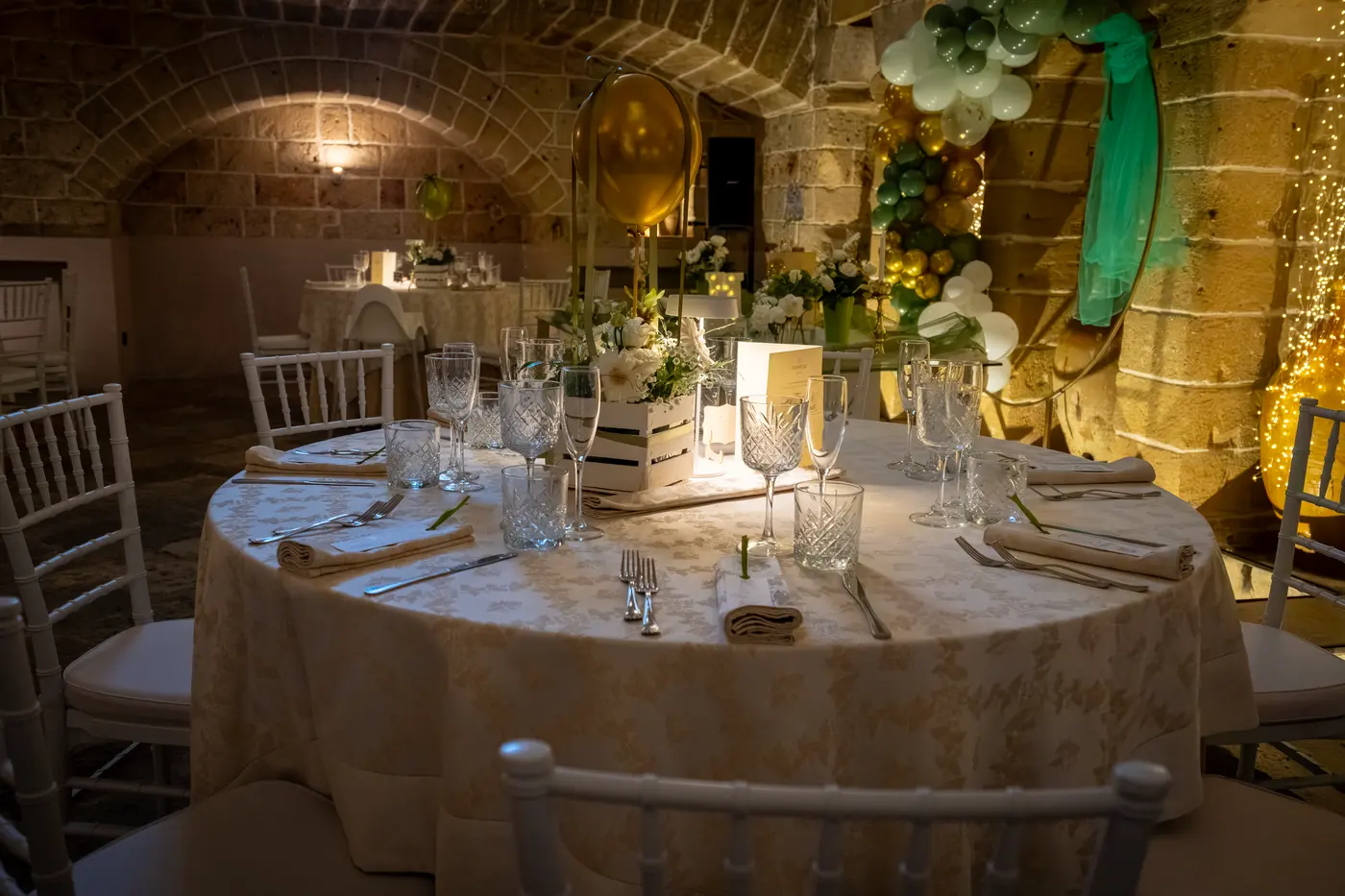 Tavolo rotondo apparecchiato con cristalli e fiori nella sala ipogea